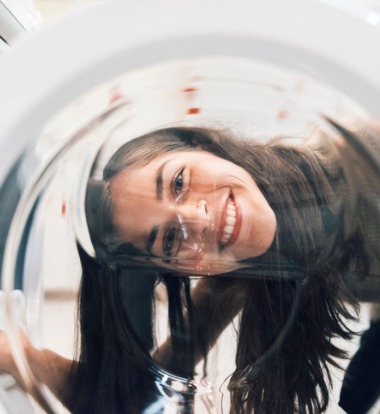 Girl Looking through Window of Commercial Washer