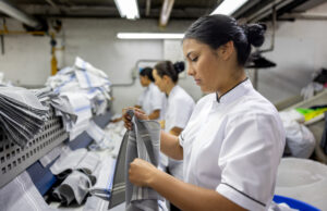 Industrial Washing Machines Minnesota, Latin American employee working at an industrial dry cleaner folding napkins for a hotel - professional cleaning concepts